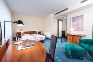 ein Hotelzimmer mit einem Tisch und einem Bett in der Unterkunft Radisson Blu Fürst Leopold Hotel in Dessau