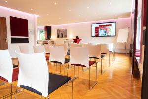 a room with white chairs and a flat screen tv at Hotel Bürger in Siegen
