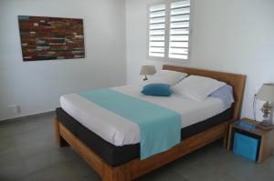 - une chambre avec un grand lit et un oreiller bleu dans l'établissement Douceurs Caraïbes, Gîte Papaye., à Bouillante