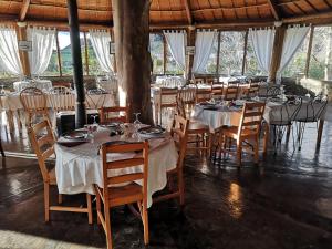 a dining room with tables and chairs with white tablecloths at Hotel os Moinhos in Velas