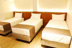 2 bedden in een kleine kamer met witte lakens bij Best Guest Hotel Expo Anhembi in Sao Paulo