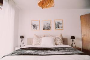 パルパンにあるAm Heimberg Skilift - Mullers x Kandahar Suiteの白いベッド1台、壁に4枚の写真が飾られたベッドルーム1室