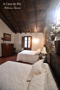 a bedroom with two beds and a stone wall at A Casa do Río in Chantada