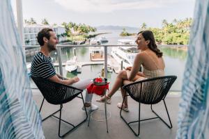 a man and a woman sitting in chairs on a balcony at The Pearl South Pacific Resort, Spa & Golf Course in Pacific Harbour