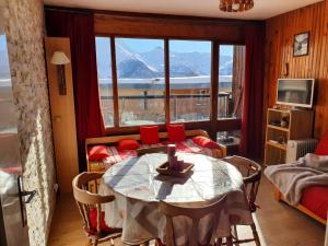 Un comedor con una mesa y un gran ventanal. en Studio Queyrelet 1 pied des pistes avec balcon & vue 2-4 personnes, en Orcières