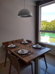 a wooden table with plates and glasses and a window at Rio Quente Flat Veredas Apto - 231 in Rio Quente