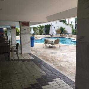 a patio with a table and umbrella next to a swimming pool at Ondina Atlantic City in Salvador