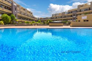 duży niebieski basen przed niektórymi budynkami apartamentowymi w obiekcie La Perla Beach Apt with Pool w mieście El Médano +12 zdjęć