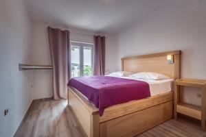 a bedroom with a bed with a purple bedspread at Apartments Bajcic in Rab