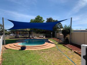 a blue canopy over a swimming pool in a yard at Orana Windmill Motel in Gilgandra