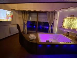 een bad met paarse verlichting in een kamer bij Le Rêve d'une Nuit suite Venise in Forbach