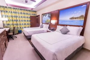 2 Betten in einem Hotelzimmer mit einem großen Fenster in der Unterkunft Surfrider Resort Hotel in Saipan