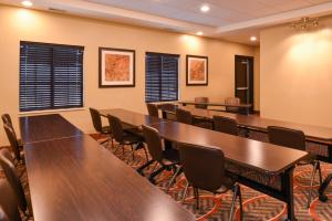 Staybridge Suites Merrillville, an IHG Hotel في ميريلفيل: قاعة اجتماعات مع طاولات وكراسي خشبية