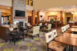 a hotel lobby with tables and chairs and a fireplace at Staybridge Suites Merrillville, an IHG Hotel in Merrillville