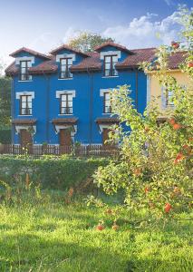 a blue house with white windows in a field at Apartamentos Rurales La Canalina in Villahormes