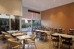 uma sala de jantar com mesas, cadeiras e janelas em Holiday Inn Express Gurugram Sector 50, an IHG Hotel em Gurgaon