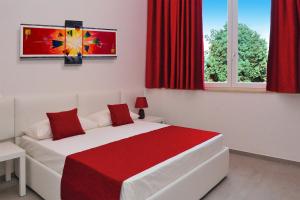 a bedroom with a white and red bed with red curtains at Chapeau Apartment in Pontecagnano