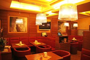 un ristorante con sedie rosse, tavoli e lampadari a braccio di Hotel Patriarchi a Aquiléia