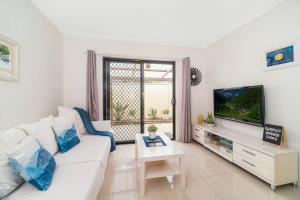 uma sala de estar com um sofá branco e uma televisão em 3 Bedrooms Holiday Home Near Sydney Airport em Sydney