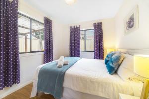 1 dormitorio con 1 cama grande y cortinas moradas en 3 Bedrooms Holiday Home Near Sydney Airport, en Sídney