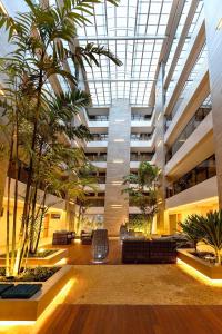 un hall avec des palmiers et des chaises dans un bâtiment dans l'établissement Eco Summer Tambaú - Apartamentos de 2 Quartos por Genius Flats, à João Pessoa