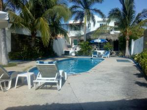 a swimming pool with lounge chairs and palm trees at Casa Marina Antonella in Pie de la Cuesta