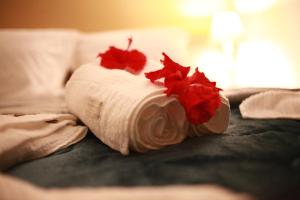 a white towel with red flowers on a bed at Pousada Aconchego Noronha in Fernando de Noronha
