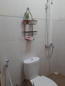 ein Badezimmer mit einem WC und einer Pflanze an der Wand in der Unterkunft Villa Blossom Kayana Regency E7 in Batu + 10 Fotos