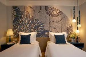 a bedroom with two beds and a mural on the wall at Sofiana My Khe Hotel & Spa- Rooftop Pool Bar in Danang
