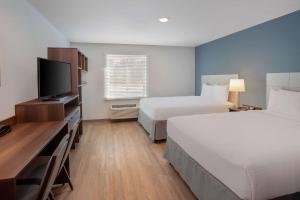 a hotel room with two beds and a flat screen tv at WoodSping Suites Washington DC East Arena Drive in Hyattsville
