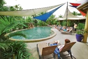 a group of people sitting in chairs around a pool at Bohemia Resort Cairns in Cairns