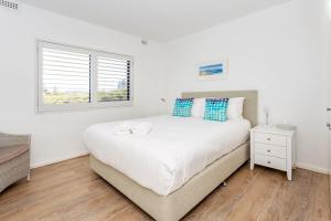 a bedroom with a large white bed and a window at Cottesloe Marine Apartment in Perth