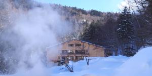 a house in the snow in front of a mountain at Tomuraushionsen Higashi Taisetsuso in Shintoku