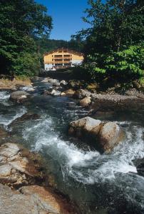 a river with rocks and a building in the background at Tomuraushionsen Higashi Taisetsuso in Shintoku