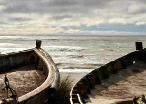 um barco sentado na praia perto do oceano em Angelo em Punta Del Diablo