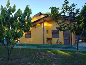 een klein geel huis met een tafel en stoelen bij Chalé Quintal Amazon in Macapá