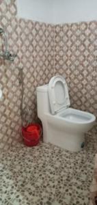 a bathroom with a toilet with a red bucket at kayastha restaurant & lodge in Bandīpur