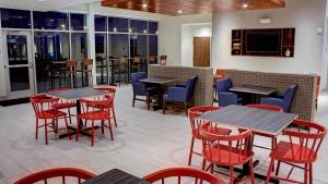 um restaurante com mesas, cadeiras vermelhas e mesa de cabeceira em Holiday Inn Express Spencer, an IHG Hotel em Spencer