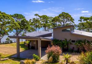 une maison sur une colline avec des arbres en arrière-plan dans l'établissement Cloudy Bay Lagoon Estate, à South Bruny