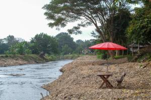 uma mesa de piquenique com um guarda-chuva ao lado de um rio em Sawasdeepai River Resort em Pai