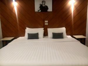 a bedroom with a large white bed with a wooden headboard at The Rodman Hotel in Chiang Mai