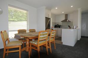 una cucina e una sala da pranzo con tavolo e sedie in legno di Cottage 45° South a Te Anau