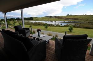 a deck with chairs and a table and a view of a lake at Cottage 45° South in Te Anau