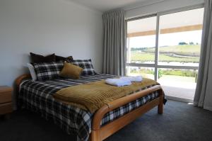 a bedroom with a bed and a large window at Cottage 45° South in Te Anau