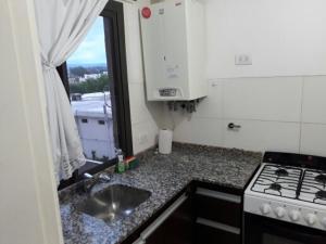 a kitchen with a stove and a sink and a window at Edificio Hipolito Irigoyen in Villa Carlos Paz
