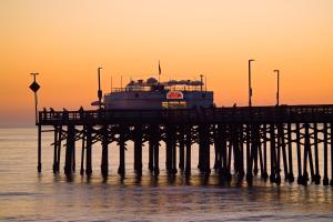 a pier with a boat in the water at sunset at Holiday Inn Express Newport Beach, an IHG Hotel in Newport Beach
