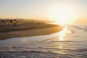 the sun is setting on the beach near the water at Holiday Inn Express Newport Beach, an IHG Hotel in Newport Beach