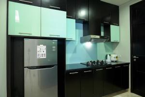 ジャカルタにあるLuxury 2BR at The Masterpiece Condominium Epicentrum Apartment By Travelioのキッチン(黒いキャビネット、ステンレス製の冷蔵庫付)