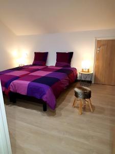 um quarto com uma cama grande com lençóis roxos e um banco em appart lièvre 4 étoiles em Cornimont