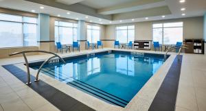 uma piscina com cadeiras azuis num edifício em Holiday Inn Express & Suites - Brantford, an IHG Hotel em Brantford